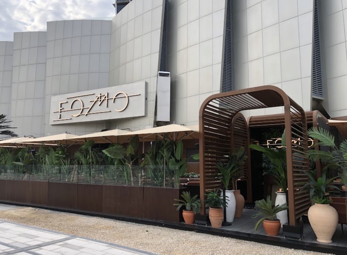 Outside Fomo Lounge — wooden entrance arch, terrace and lush plants in Oud Metha, Dubai